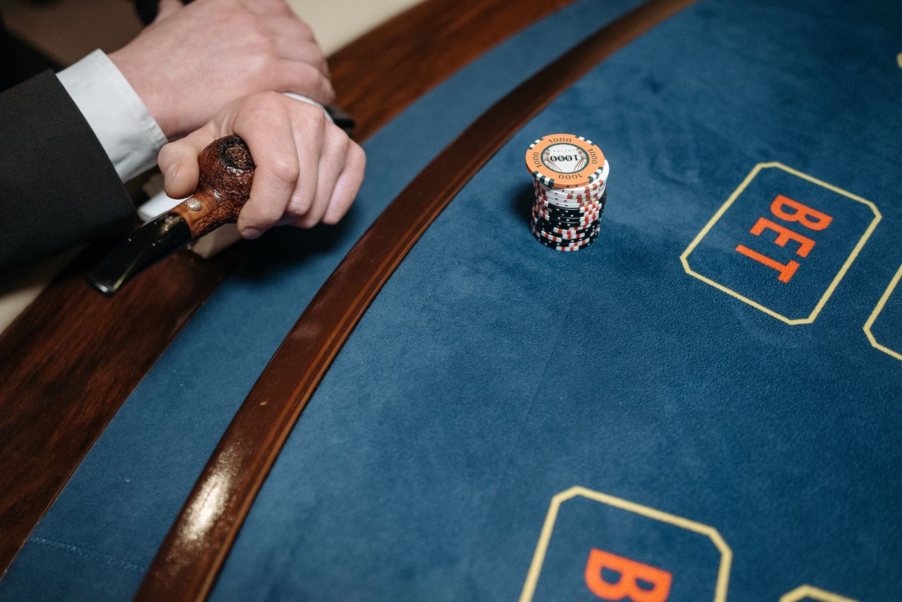 Detailed view of a casino gaming table with poker chips and a wooden pipe on the side.